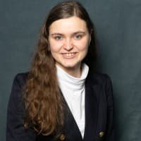 Profilová fotka Sarah Mayrhofer na LinkedIn — tmavé sako na zeleném pozadí