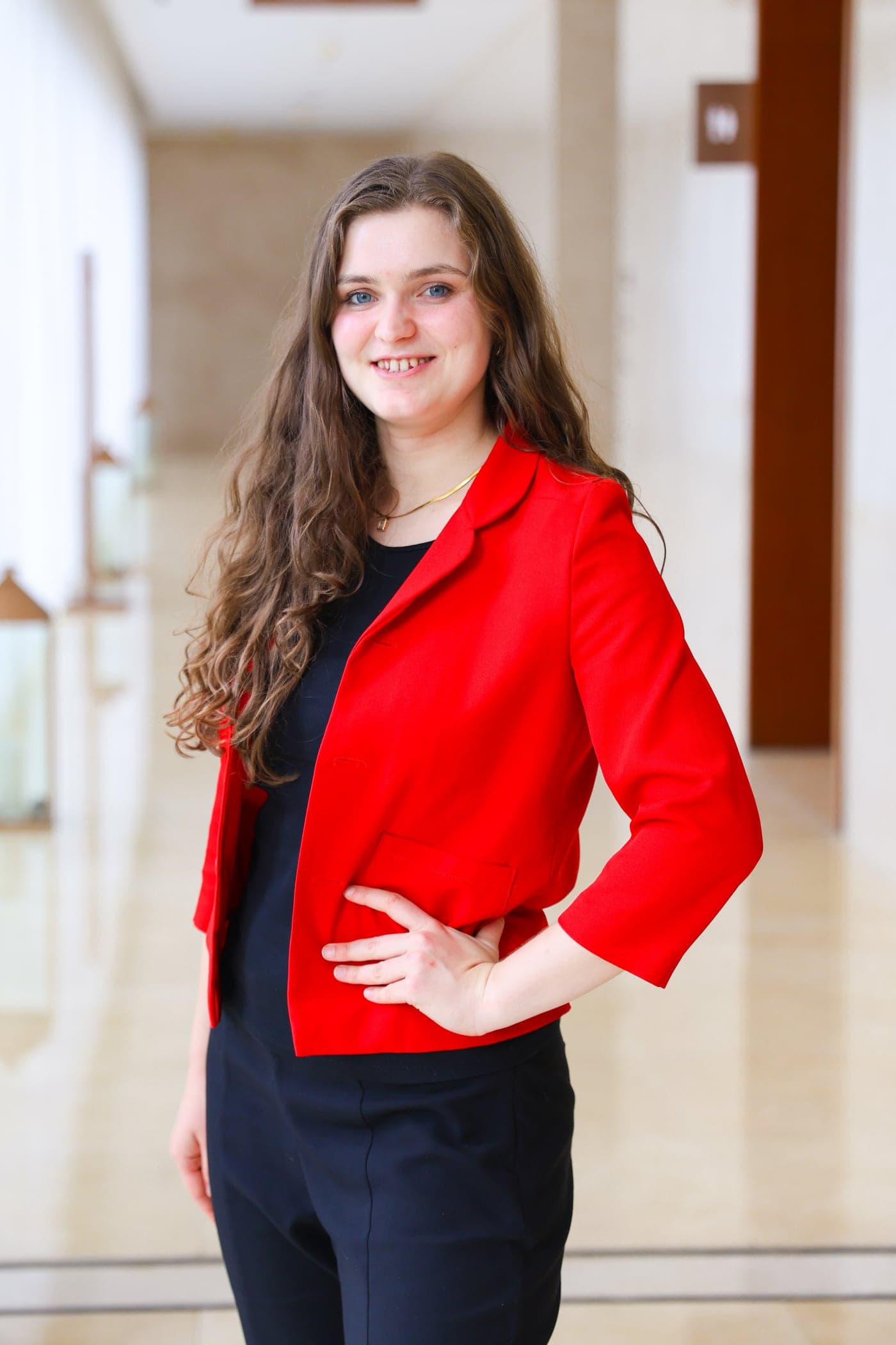 Sarah Mayrhofer im roten Blazer in einem hellen Gang